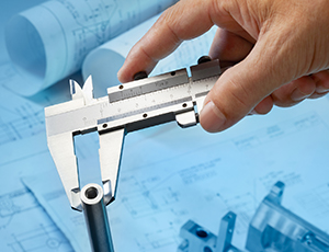 measuring machine part with caliper blueprint as background